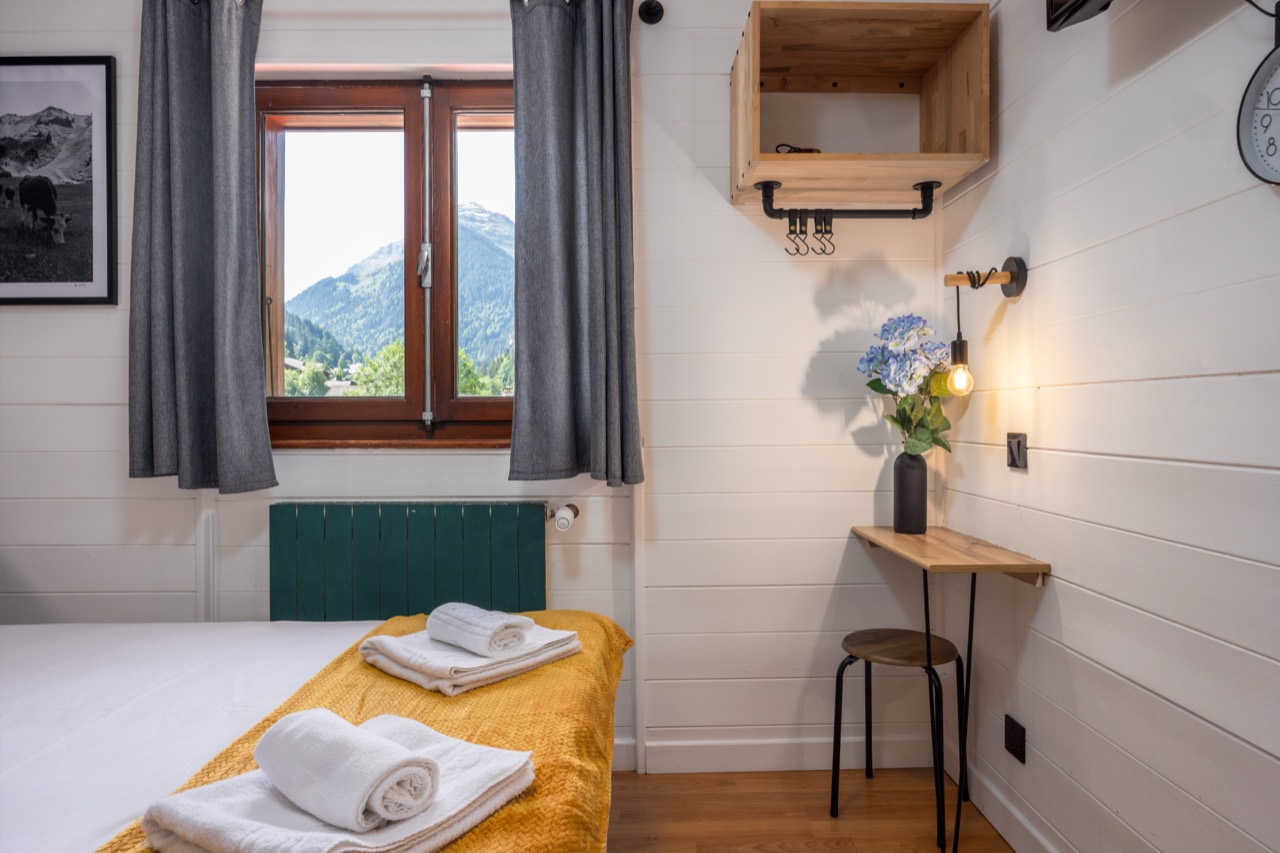 A room at Les Rhodos, white walls and a window onto the mountain